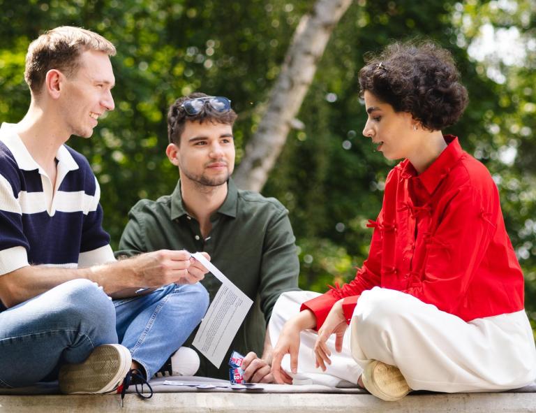 Studia i praktyki za granicą | Uniwersytet WSB Merito Szczecin: Trzech studentów Uniwersytetu WSB Merito Poznań dyskutuje na świeżym powietrzu.