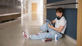 Nasz kampus | Uniwersytet WSB Merito w Toruniu: Główna grafika: Toruń - studia I stopnia - student siedzący na korytarzu