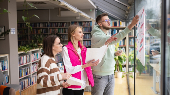 Sprzedaż i e-commerce | Studia II stopnia w Toruniu | Uniwersytet WSB Merito w Toruniu: Główna grafika: Toruń - studia I stopnia - grupa uśmiechniętych studentów w bibliotece