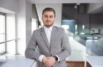 Cyfrowy uniwersytet | Uniwersytet WSB Merito w Toruniu: elegancko ubrany student na korytarzu uniwersytetu