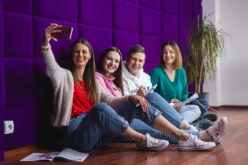 Strona główna | Uniwersytet WSB Merito w Toruniu: 4 studentów WSB Merito w Toruniu siedzi w strefie studenta i robią sobie zdjęcie