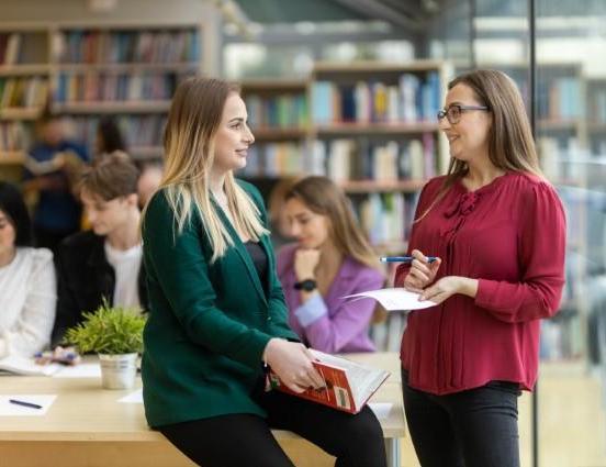 Studia I stopnia w Toruniu | Uniwersytet WSB Merito w Toruniu: Studentki rozmawiają w bibliotece Uniwersytetu WSB Merito w Toruniu