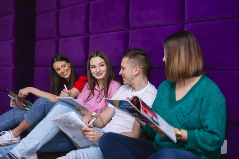 Logistyka służb mundurowych | Studia I stopnia w Toruniu | Uniwersytet WSB Merito w Toruniu: Grupa studentów siedzi z książkami na fioletowym tle