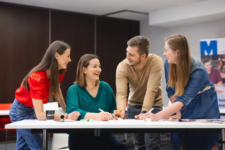 Architekt systemów informatycznych dla biznesu | Studia I stopnia w Toruniu | Uniwersytet WSB Merito w Toruniu: Główna grafika: Toruń - studia I stopnia - grupa uśmiechniętych studentów podczas projektu