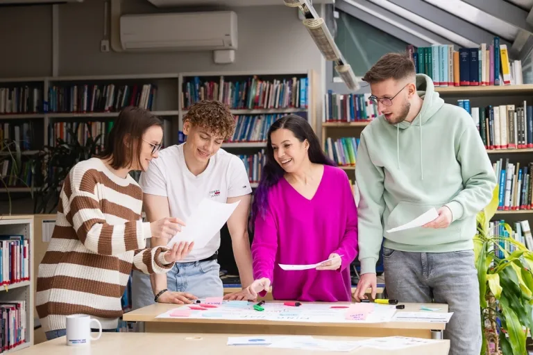 Gospodarowanie nieruchomościami | Studia I stopnia w Toruniu | Uniwersytet WSB Merito w Toruniu: Główna grafika: Toruń - studia I stopnia - grupa uśmiechniętych studentów w bibliotece