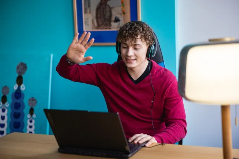 Informatyka w biznesie | Studia I stopnia w Toruniu | Uniwersytet WSB Merito w Toruniu: Główna grafika: Toruń - studia I stopnia - student witający się z uczestnikami online zajęć