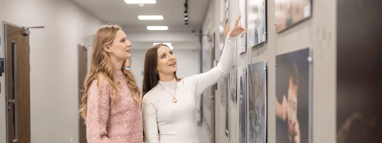Wystawa prac studentów kierunku design w biznesie | 14-28 listopada  [GALERIA ZDJĘĆ] | Aktualności | Uniwersytet WSB Merito w Toruniu: zapowiedź wystawy prac studentów kierunku design w biznesie - dwie osoby rozmawiają przy obrazach
