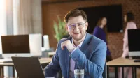 Analityk finansowy | Studia podyplomowe w Warszawie | Uniwersytet WSB Merito Warszawa: uśmiechnięty mężczyzna siedzący przed laptopem