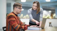 Sztuczna inteligencja w biznesie | Studia podyplomowe w Warszawie | Uniwersytet WSB Merito Warszawa: kobieta pokazująca mężczyźnie ekran laptopa