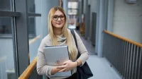 Organizacja i zarządzanie oświatą | Studia podyplomowe w Warszawie | Uniwersytet WSB Merito Warszawa: kobieta trzymająca laptop w rękach