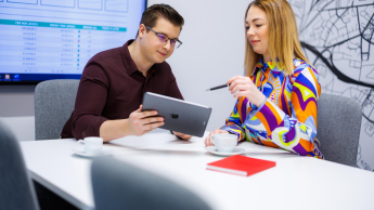 Zarządzanie produktem | Studia II stopnia w Warszawie | Uniwersytet WSB Merito Warszawa: Studentka i student z ipad siedzacy przy stole z 