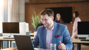Bankowość cyfrowa | Studia podyplomowe w Warszawie | Uniwersytet WSB Merito Warszawa: zadowolony mężczyzna patrzący w ekran laptopa