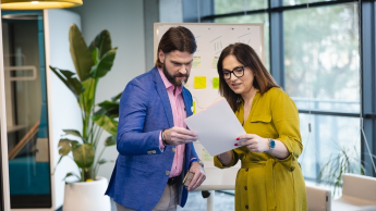 Zintegrowany system informatyczny SAP ERP | Studia podyplomowe w Warszawie | Uniwersytet WSB Merito Warszawa: kobieta i mężczyzna analizujący dokument
