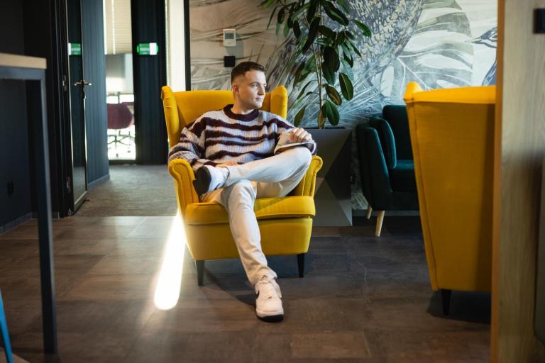 Biblioteka | Uniwersytet WSB Merito Warszawa: Student siedzi na żółtym fotelu 