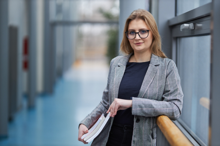 Product Manager w erze AI - zarządzanie produktami cyfrowymi | Studia podyplomowe w Warszawie | Uniwersytet WSB Merito Warszawa: uśmiechnięta kobieta trzymająca książki