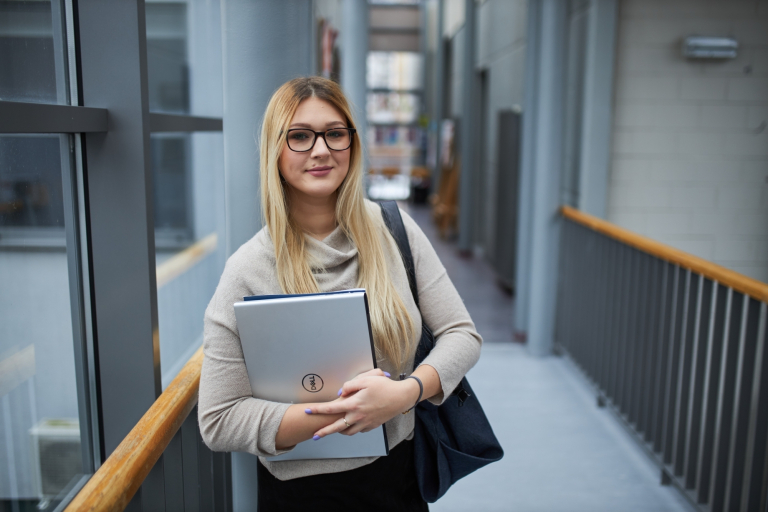 Inżynieria oprogramowania w JavaScript (TypeScript) | Studia podyplomowe w Warszawie | Uniwersytet WSB Merito Warszawa: kobieta trzymająca laptop w rękach