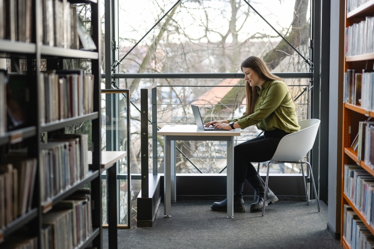 Audyt wewnętrzny i kontrola w organizacji | Studia podyplomowe w Warszawie | Uniwersytet WSB Merito Warszawa: Studentka pracująca w bibliotece.