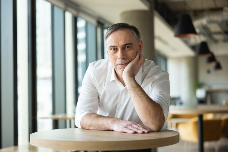 Doradca w procesie sukcesji | Studia podyplomowe w Warszawie | Uniwersytet WSB Merito Warszawa: uczestnik MBA pozuje przy stole