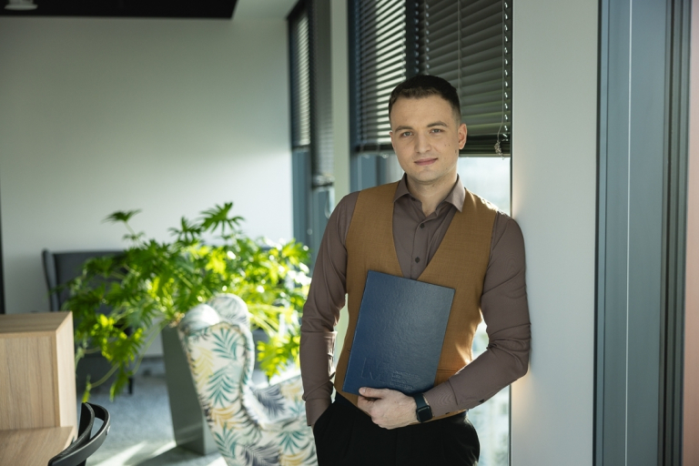 Stypendia i zniżki | Uniwersytet WSB Merito Warszawa: Student WSB Merito trzyma dyplom w ręce z uśmiechem na twarzy