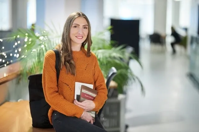 Zarządzanie projektami | Studia II stopnia w Warszawie | Uniwersytet WSB Merito Warszawa: Siedząca studentka z książkami