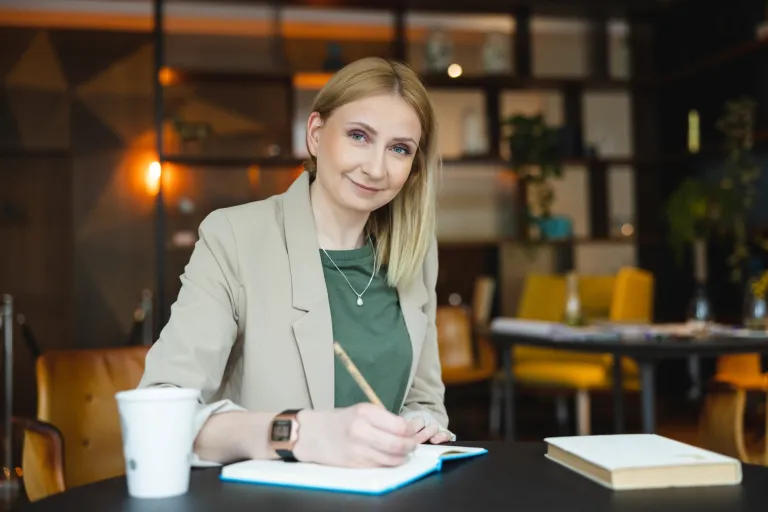 Prawo nowych technologii | Studia I stopnia w Warszawie | Uniwersytet WSB Merito Warszawa: uśmiechnięta kobieta notująca notatki