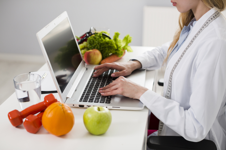 Nutripsychiatria | Studia podyplomowe we Wrocławiu | Uniwersytet WSB Merito we Wrocławiu: Kobieta pracująca na laptopie wśród warzyw i owoców