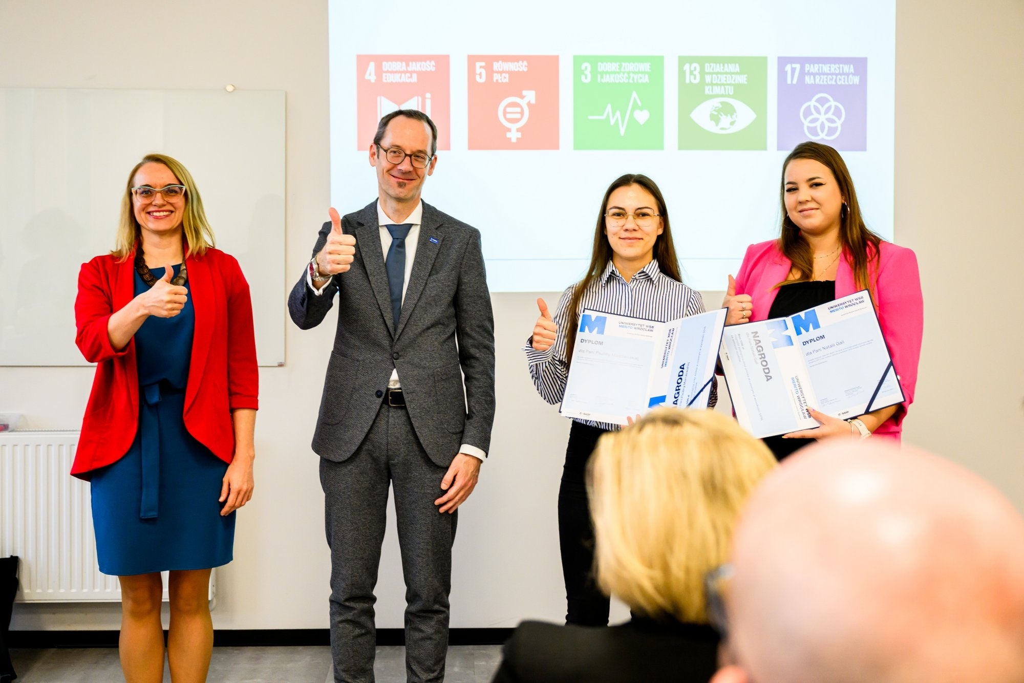 Laureatki konkursu Paulina Marczewska i Natalia Gala odbierają nagrody od Jana Eberhardta prezesa zarządu BASF Catalysts Polska oraz Agaty Natalli zastępcy kanclerza Uniwersytetu WSB Merito.