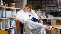 International Management | Studia II stopnia we Wrocławiu | Uniwersytet WSB Merito we Wrocławiu: student w bibliotece czytający książkę