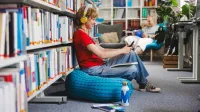 Zintegrowana terapia i  wsparcie osób z  ADHD | Studia podyplomowe we Wrocławiu | Uniwersytet WSB Merito we Wrocławiu: studentka słuchająca muzyki w bibliotece
