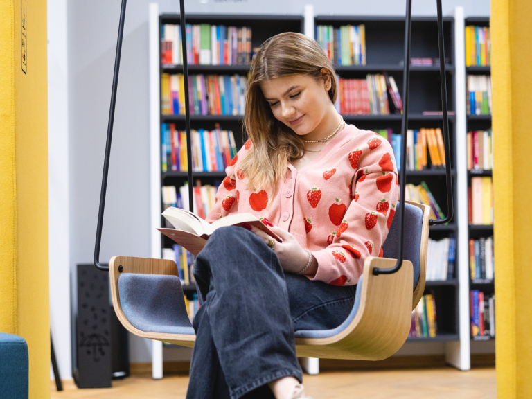 Pedagogika terapeutyczna z elementami neuroedukacji | Studia I stopnia we Wrocławiu | Uniwersytet WSB Merito we Wrocławiu: studentka czytająca książkę w bibliotece