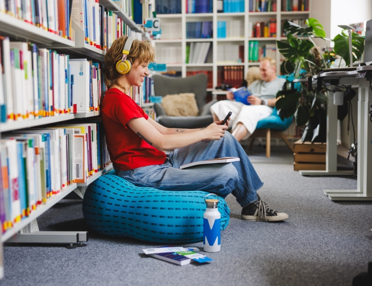 Inżynieria programowania procesorów | Studia I stopnia we Wrocławiu | Uniwersytet WSB Merito we Wrocławiu: studentka słuchająca muzyki w bibliotece