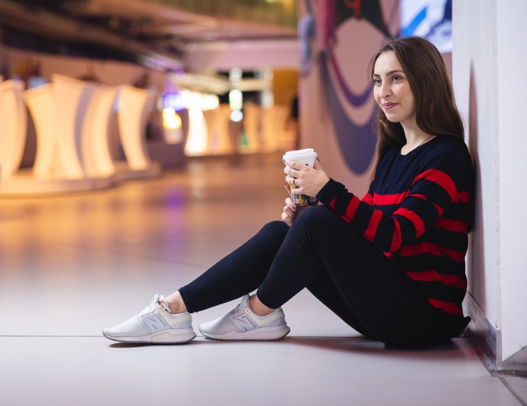 Inteligentna logistyka produkcji | Studia I stopnia we Wrocławiu | Uniwersytet WSB Merito we Wrocławiu: studentka siedząca na ziemi i pijąca kawę