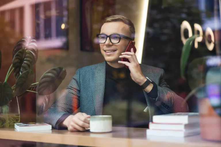 Służby i bezpieczeństwo publiczne | Studia II stopnia ze studiami podyplomowymi  | Uniwersytet WSB Merito we Wrocławiu: student w kawiarni rozmawiający przez telefon