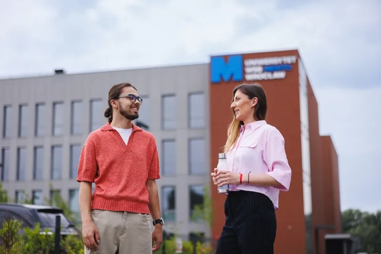 studenci rozmawiający ze sobą przed budynkiem uczelni